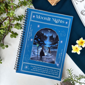 A4 spiral notebook with a midnight-blue "Moonlit Nights" cover featuring an illustrated starry forest path with a lone figure and lanterns, framed with sparkle and crystal details, and a reflective quote at the bottom.