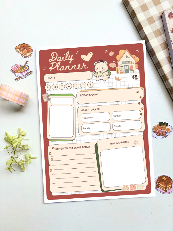A5 daily planner with a terracotta cover featuring an illustrated bear and cottage design, including sections for date, goals, meal tracking, to-do list, and reminders.