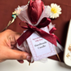 Handcrafted burgundy tulip-shaped scented candle presented as a single-stem bouquet, wrapped in net with a satin ribbon bow
