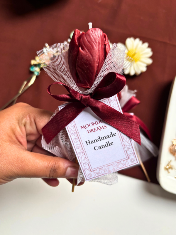 Handcrafted burgundy tulip-shaped scented candle presented as a single-stem bouquet, wrapped in net with a satin ribbon bow