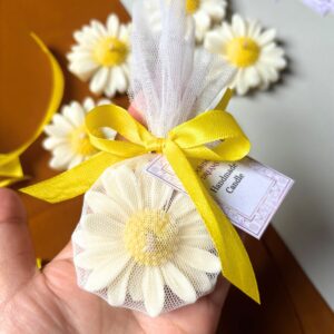 Handcrafted daisy-shaped candle with white petals and a yellow textured centre, wrapped in net with a customisable gift tag.