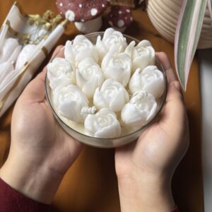 Handcrafted wide thali jar candle with a bunch of sculpted tulips, glowing softly on a table